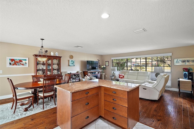 kitchen with light stone counters, a kitchen island, pendant lighting, and light hardwood / wood-style floors