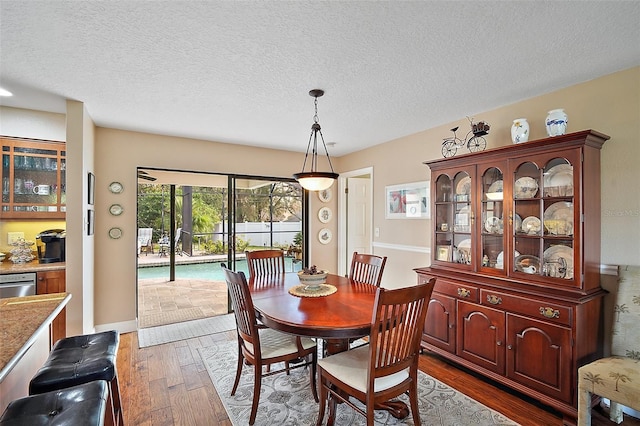 dining area with a textured ceiling and dark wood-type flooring