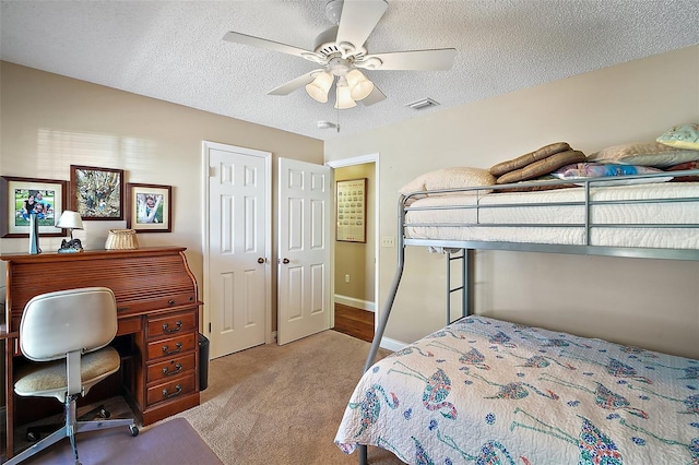 bedroom featuring light carpet, a textured ceiling, and ceiling fan