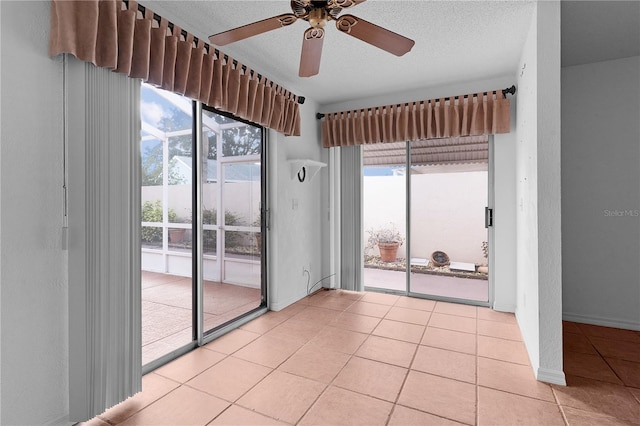 tiled empty room featuring a textured ceiling and ceiling fan