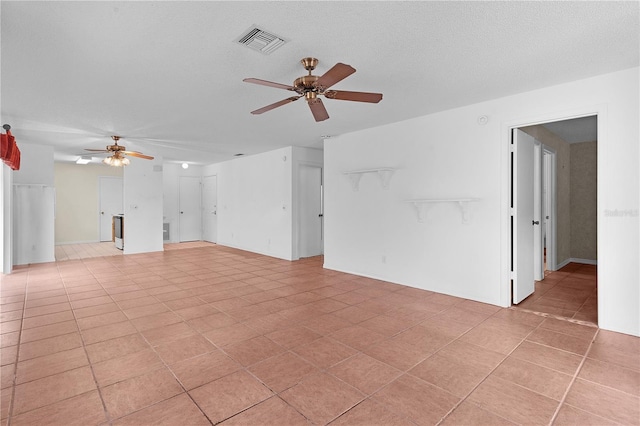 tiled empty room featuring ceiling fan and a textured ceiling