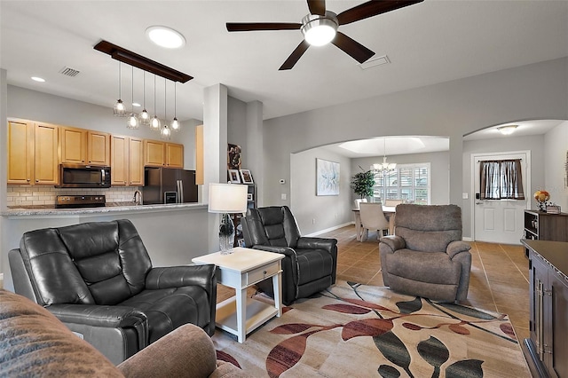 living room featuring ceiling fan with notable chandelier and tile patterned floors