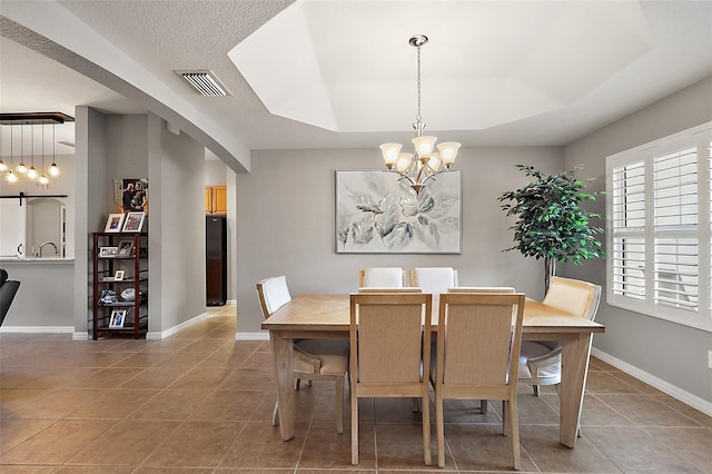 dining room with tile patterned flooring, a raised ceiling, and a notable chandelier