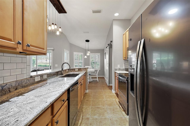 kitchen featuring sink, tasteful backsplash, a barn door, pendant lighting, and appliances with stainless steel finishes