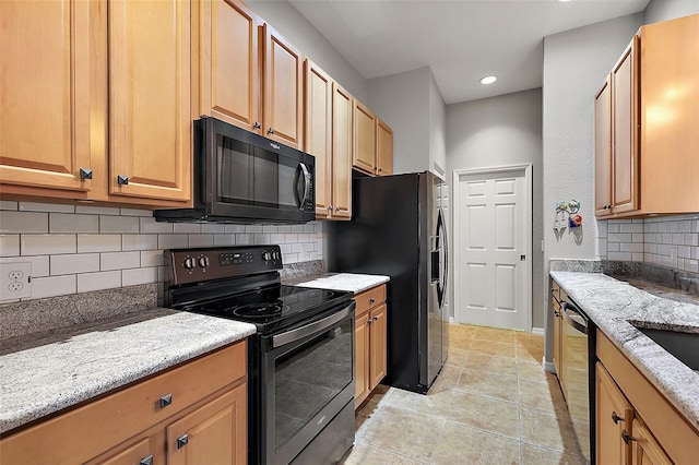 kitchen with black appliances, light stone counters, and backsplash