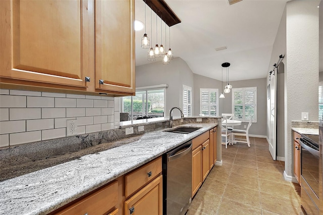 kitchen featuring light stone countertops, stainless steel appliances, sink, pendant lighting, and a barn door