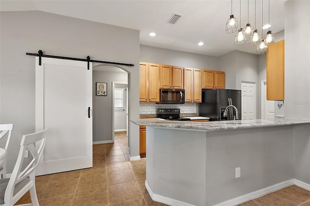 kitchen featuring decorative backsplash, light stone countertops, black appliances, a barn door, and light tile patterned flooring