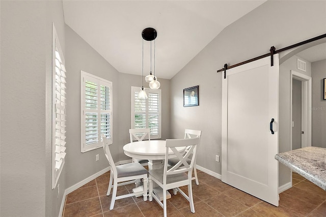 dining room featuring tile patterned flooring, a barn door, and vaulted ceiling