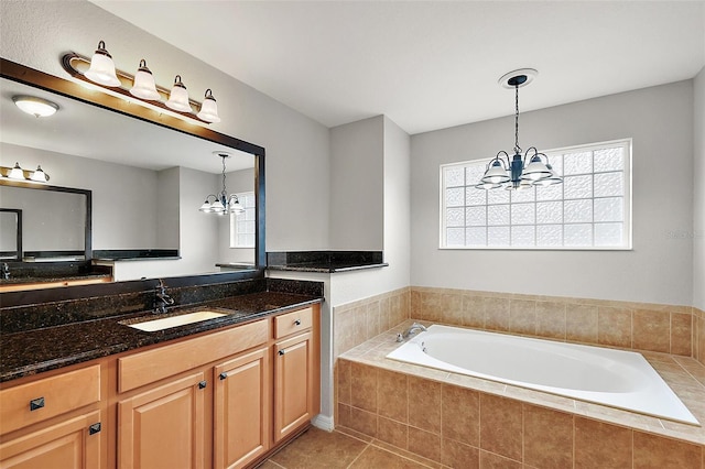 bathroom featuring tiled bath, tile patterned flooring, vanity, and a chandelier