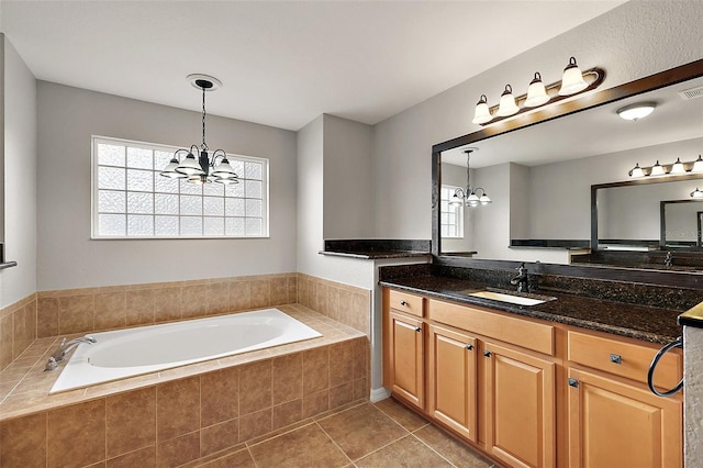 bathroom featuring tiled tub, tile patterned flooring, vanity, and an inviting chandelier