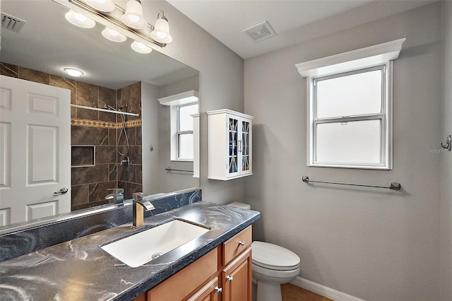 bathroom featuring vanity, toilet, and tiled shower