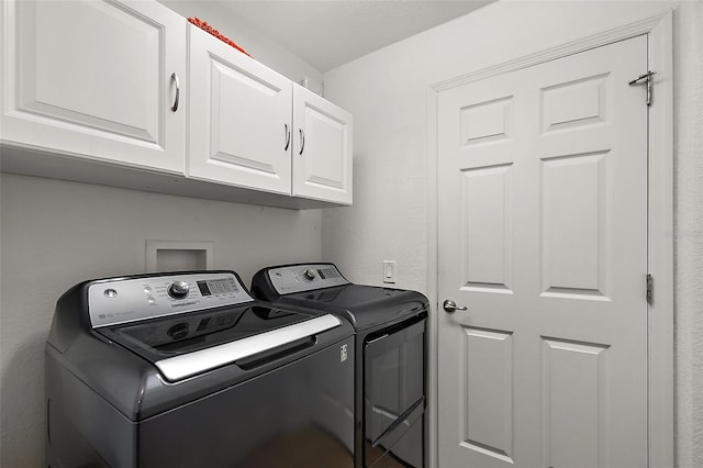 washroom with washing machine and clothes dryer and cabinets