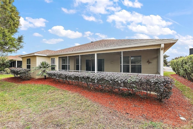 rear view of house featuring a sunroom and a yard