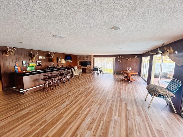 interior space with indoor bar, light hardwood / wood-style floors, and wood walls