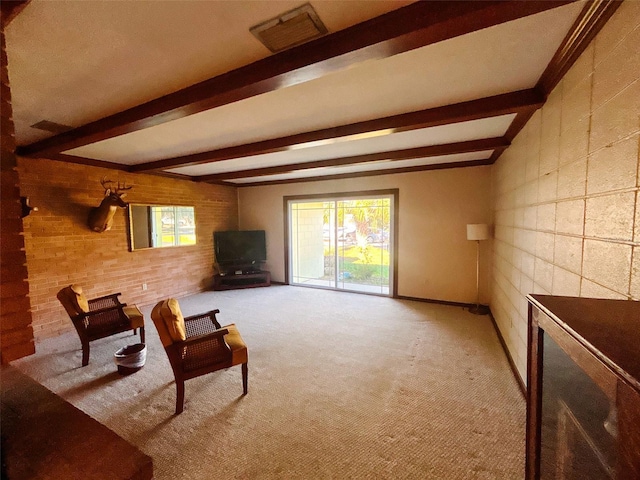 sitting room featuring beamed ceiling, light colored carpet, and a wealth of natural light