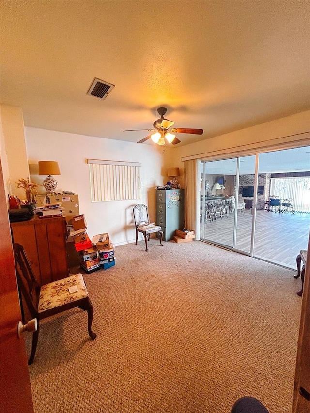 sitting room featuring carpet flooring, ceiling fan, and a textured ceiling