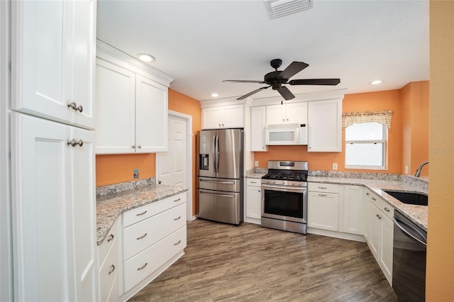 kitchen featuring sink, stainless steel appliances, white cabinetry, and light stone countertops