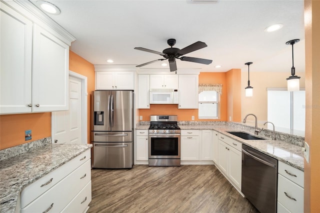 kitchen with hanging light fixtures, sink, white cabinets, dark wood-type flooring, and stainless steel appliances