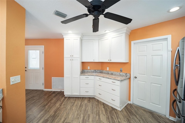 kitchen with light stone counters, white cabinetry, stainless steel fridge, and dark hardwood / wood-style flooring