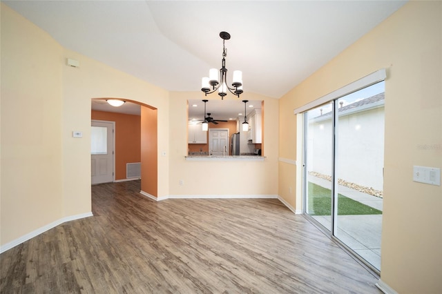 interior space with vaulted ceiling, ceiling fan with notable chandelier, and hardwood / wood-style floors