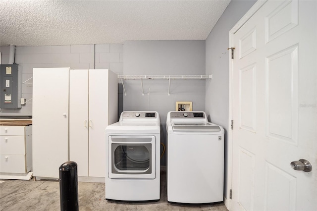 washroom featuring electric panel, a textured ceiling, and independent washer and dryer