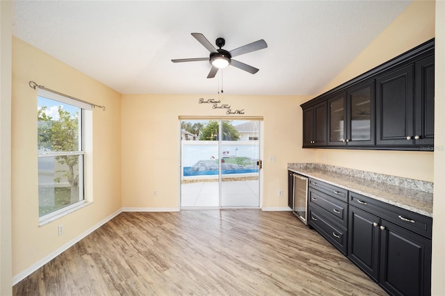 kitchen featuring light hardwood / wood-style floors, light stone counters, ceiling fan, and wine cooler