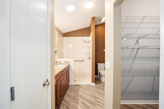 bathroom with lofted ceiling, vanity, a shower, toilet, and hardwood / wood-style flooring