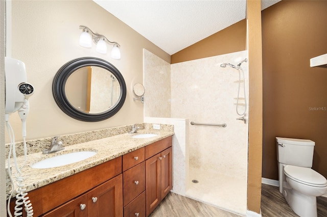 bathroom featuring wood-type flooring, toilet, walk in shower, vanity, and lofted ceiling