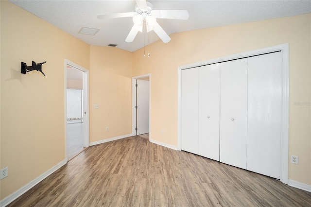 unfurnished bedroom with wood-type flooring, vaulted ceiling, ceiling fan, a textured ceiling, and a closet