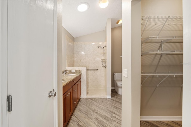 17159 SE 78th Crowfield Ave, The Villages, FL 32162 - full bathroom featuring vaulted ceiling, a tile shower, a spacious closet, toilet, and wood finished floors