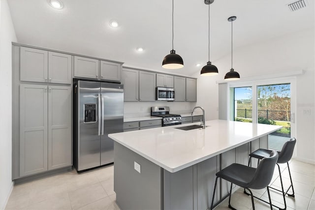 kitchen featuring stainless steel appliances, gray cabinets, hanging light fixtures, and sink