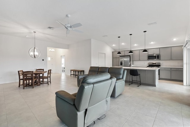 living room featuring ceiling fan with notable chandelier, light tile patterned flooring, lofted ceiling, and sink