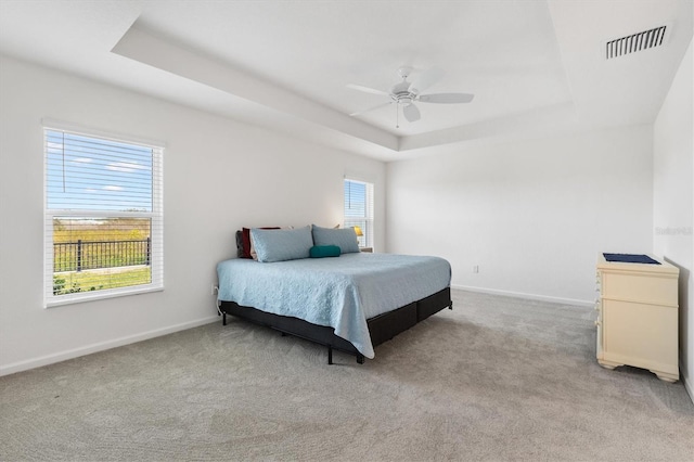 carpeted bedroom featuring a raised ceiling and ceiling fan