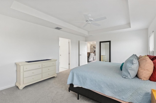 bedroom with ceiling fan, light carpet, and a tray ceiling