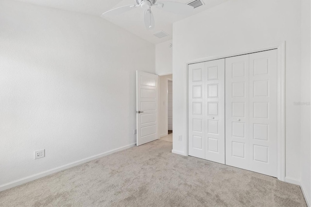 unfurnished bedroom featuring ceiling fan, a closet, light carpet, and vaulted ceiling