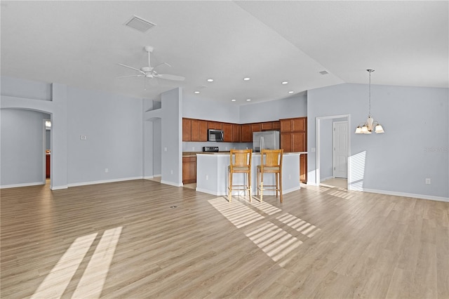 unfurnished living room featuring ceiling fan with notable chandelier, light wood-type flooring, and high vaulted ceiling