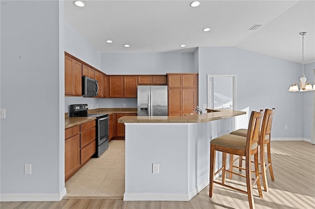 kitchen with stainless steel appliances, a chandelier, pendant lighting, a breakfast bar, and a center island with sink