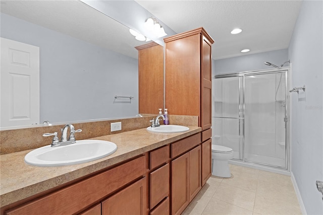 bathroom with tile patterned floors, vanity, a shower with shower door, and toilet