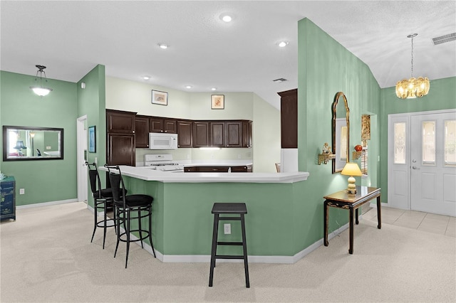 kitchen featuring a breakfast bar area, light colored carpet, dark brown cabinets, pendant lighting, and white appliances