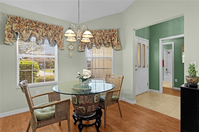 tiled dining area with lofted ceiling, a healthy amount of sunlight, and a notable chandelier