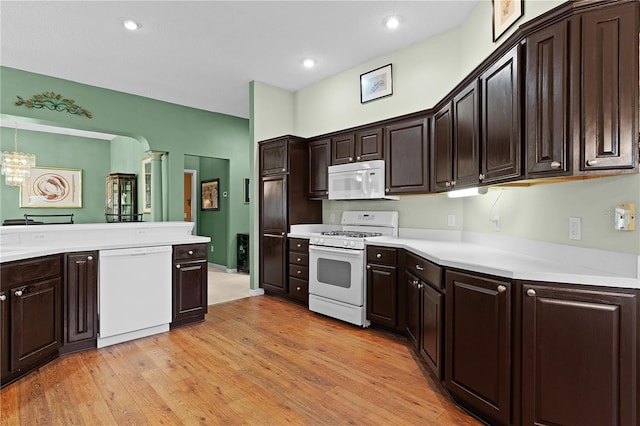 kitchen with dark brown cabinets, white appliances, and light wood-type flooring