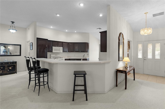 kitchen featuring white appliances, light carpet, a kitchen breakfast bar, dark brown cabinets, and light countertops
