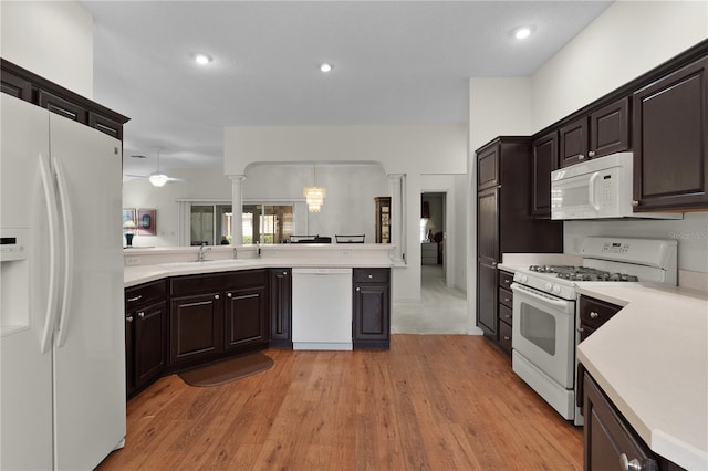 kitchen with white appliances, a sink, light countertops, light wood-style flooring, and recessed lighting