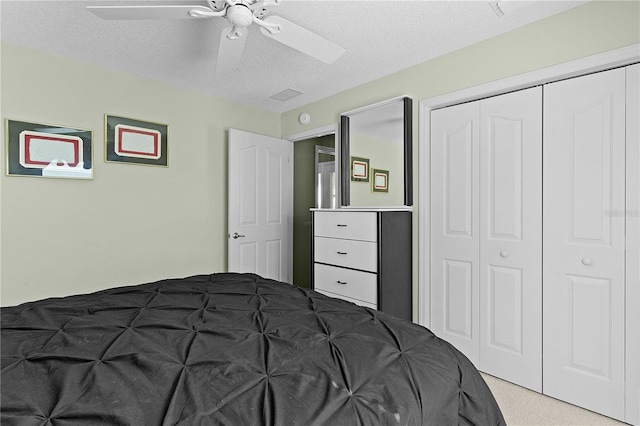 bedroom with a closet, a textured ceiling, ceiling fan, and light colored carpet