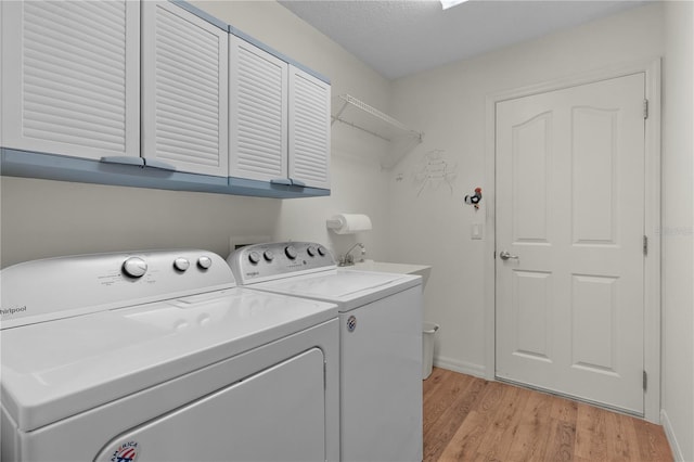 laundry room with light wood-style floors, independent washer and dryer, cabinet space, and baseboards