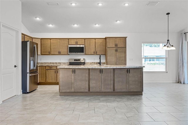 kitchen featuring hanging light fixtures, stainless steel appliances, a center island with sink, and sink