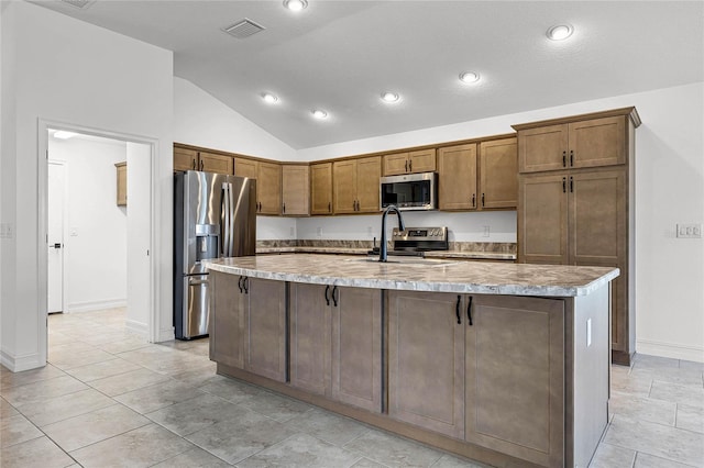 kitchen featuring sink, an island with sink, lofted ceiling, and appliances with stainless steel finishes