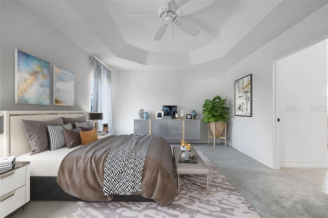 bedroom featuring ceiling fan, light carpet, and a tray ceiling