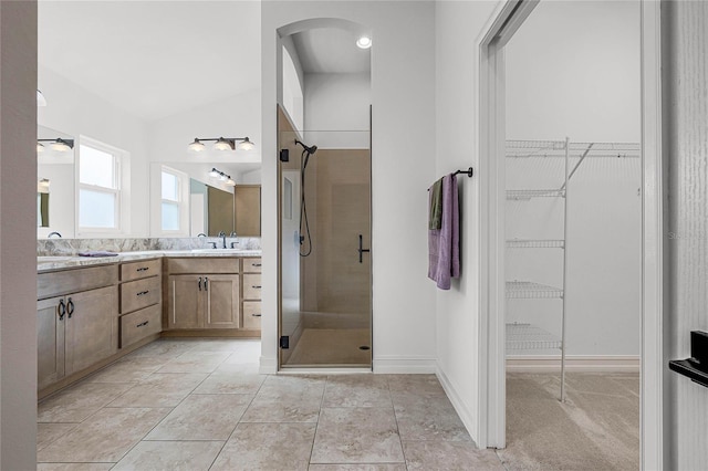 bathroom with vanity, ceiling fan, lofted ceiling, and walk in shower