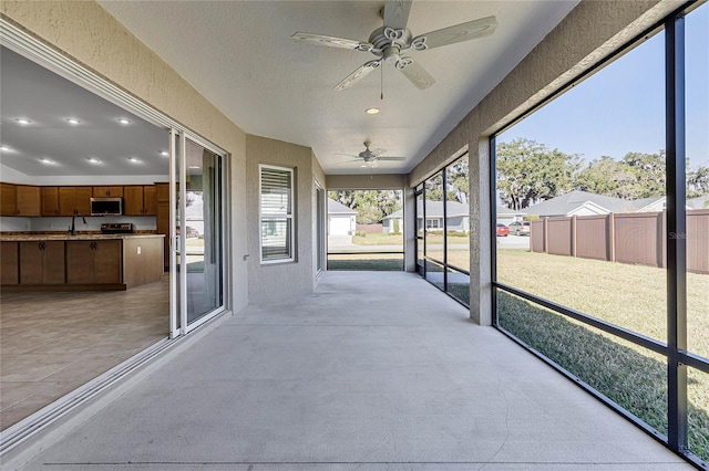 unfurnished sunroom featuring ceiling fan